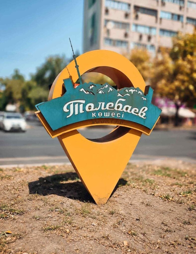 Colorful location marker for Tole Bi Walking Street featuring Almaty’s skyline and mountain silhouettes.