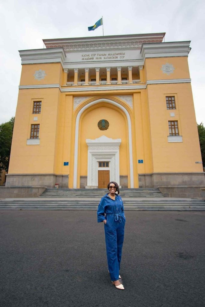 Woman traveler standing in front of the Academy of Sciences building in Almaty, Kazakhstan.
