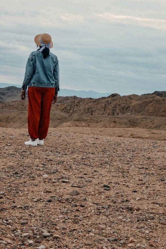 Black woman in a sun hat overlooking the rugged desert mountains of Kazakhstan.