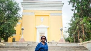 Woman standing outside a yellow historic building in Almaty during a Kazakhstan travel itinerary.