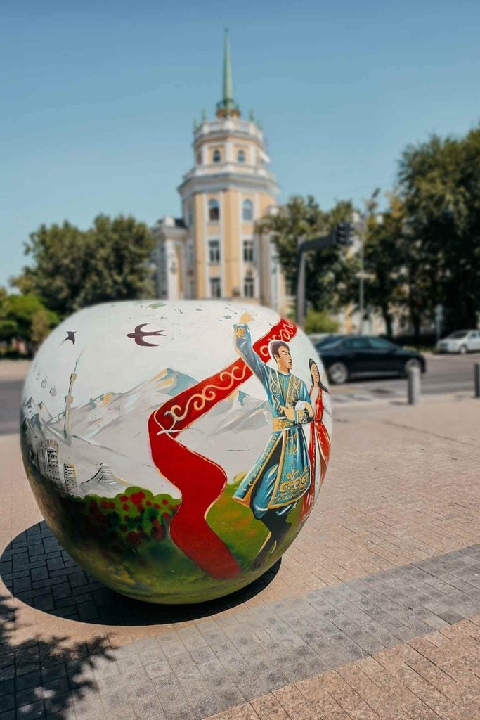 Painted apple sculpture depicting Kazakh culture on a sunny street in Almaty, Kazakhstan.