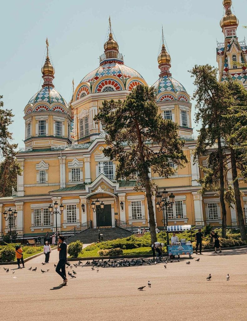 Colorful exterior of Ascension Cathedral surrounded by trees in Panfilov Park, Almaty, Kazakhstan.