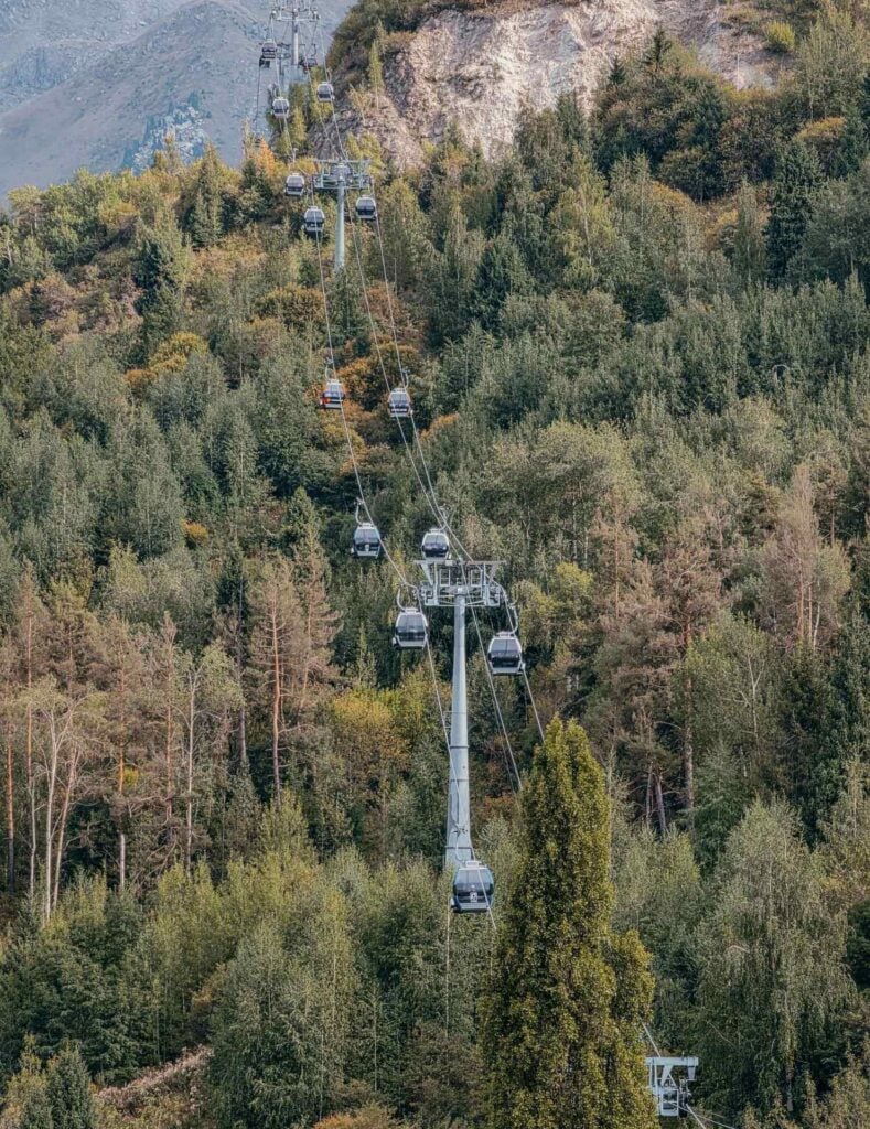 Cable cars traveling toward rocky mountain peaks at Shymbulak Mountain Resort near Almaty, Kazakhstan.